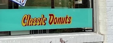 The painted window band at World's Fair Donuts: the words Classic Donuts in red lettering on turquoise